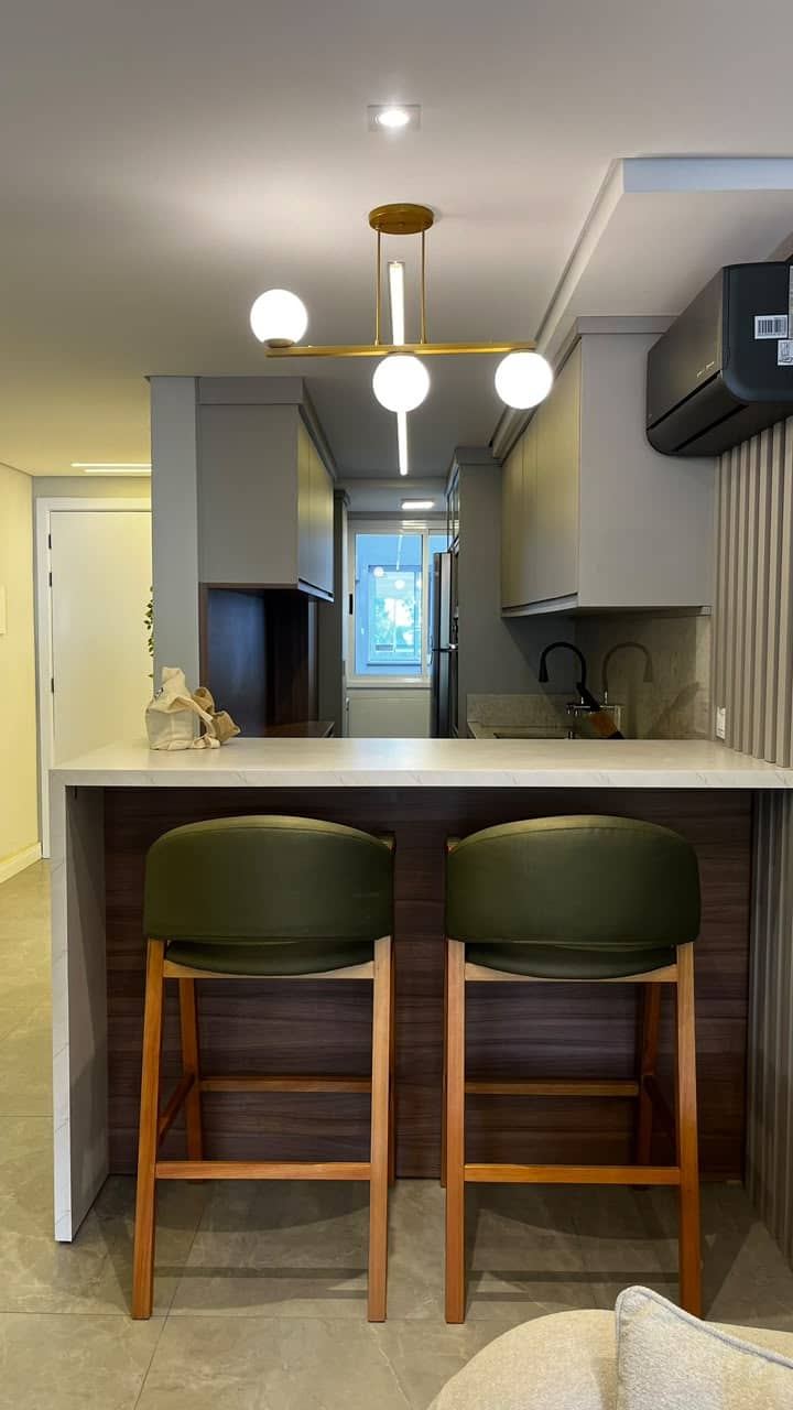 Cozinha integrada com bancada e banquetas verdes