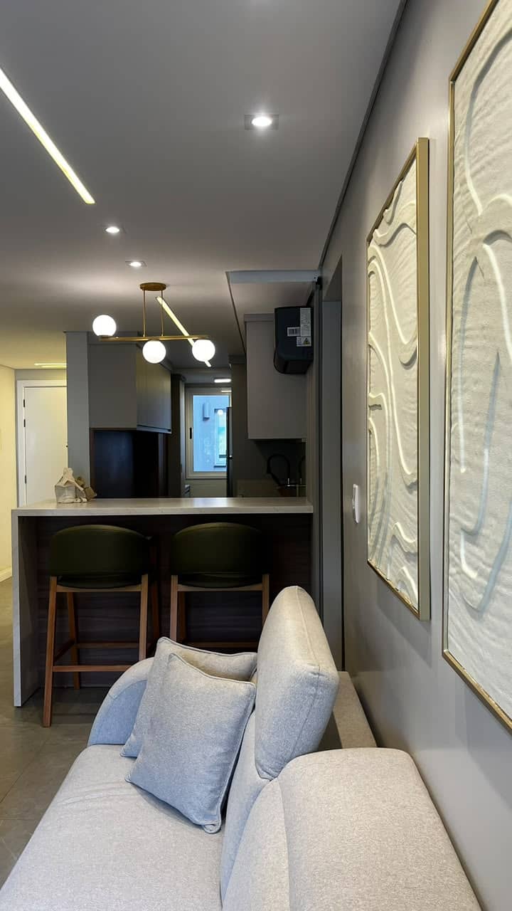 Cozinha vista da sala, com sofá e quadros em relevo