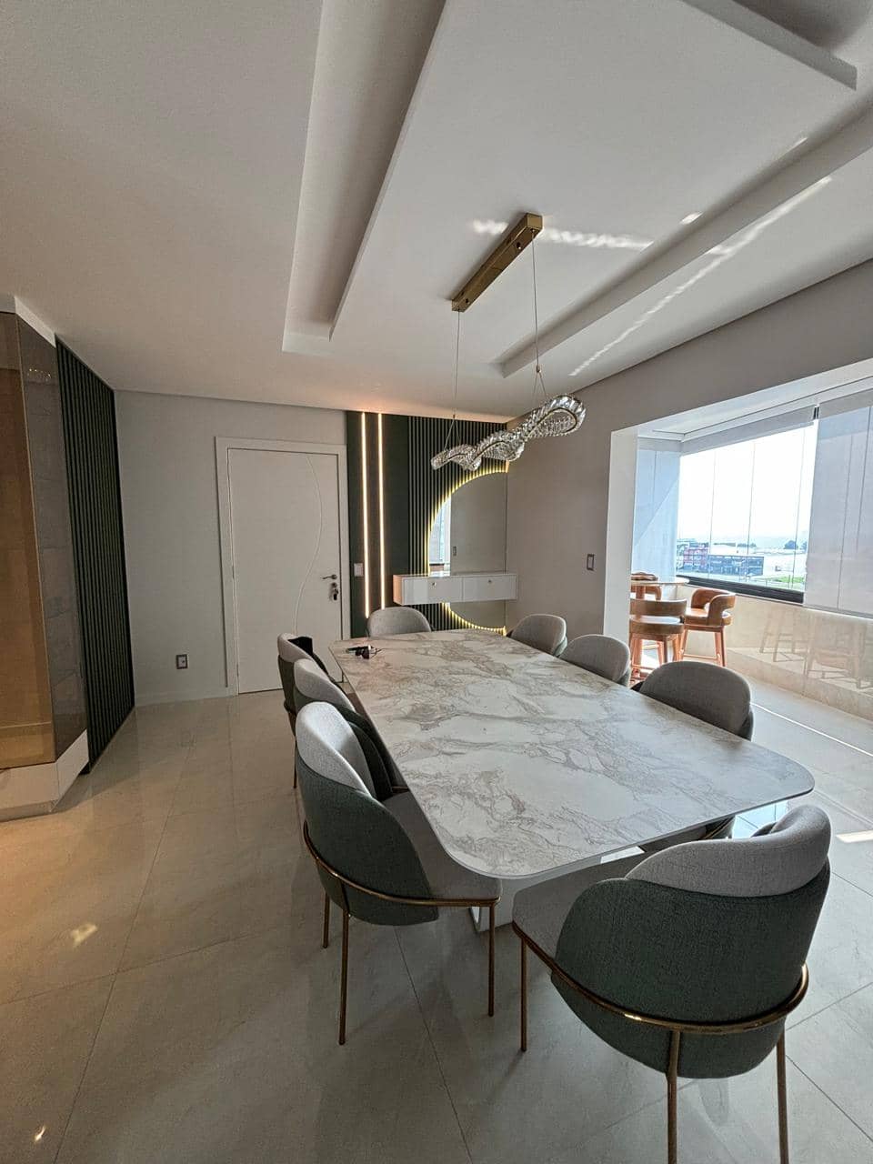 Sala de jantar com lustre sinuoso e janela ao fundo