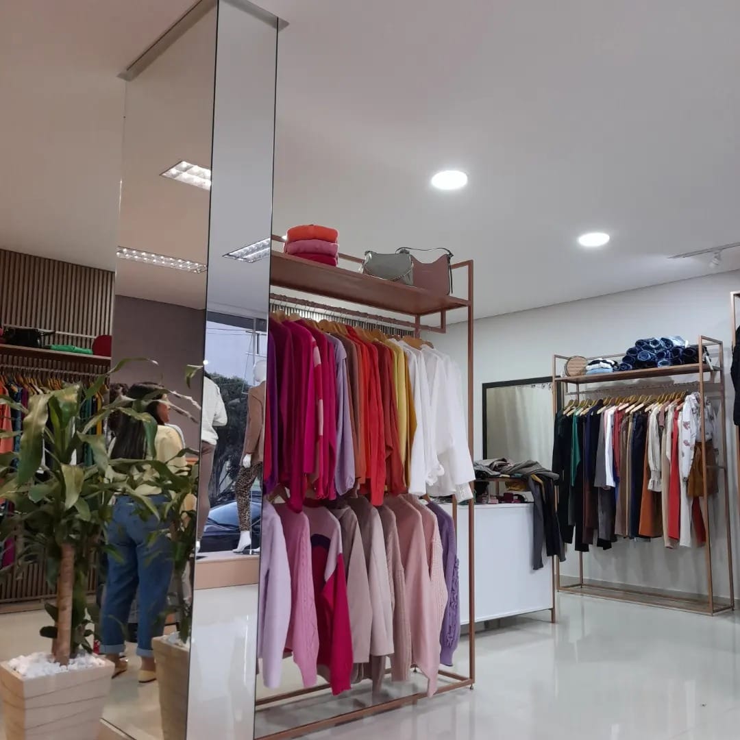 Loja de roupas com araras em rose gold e espelho