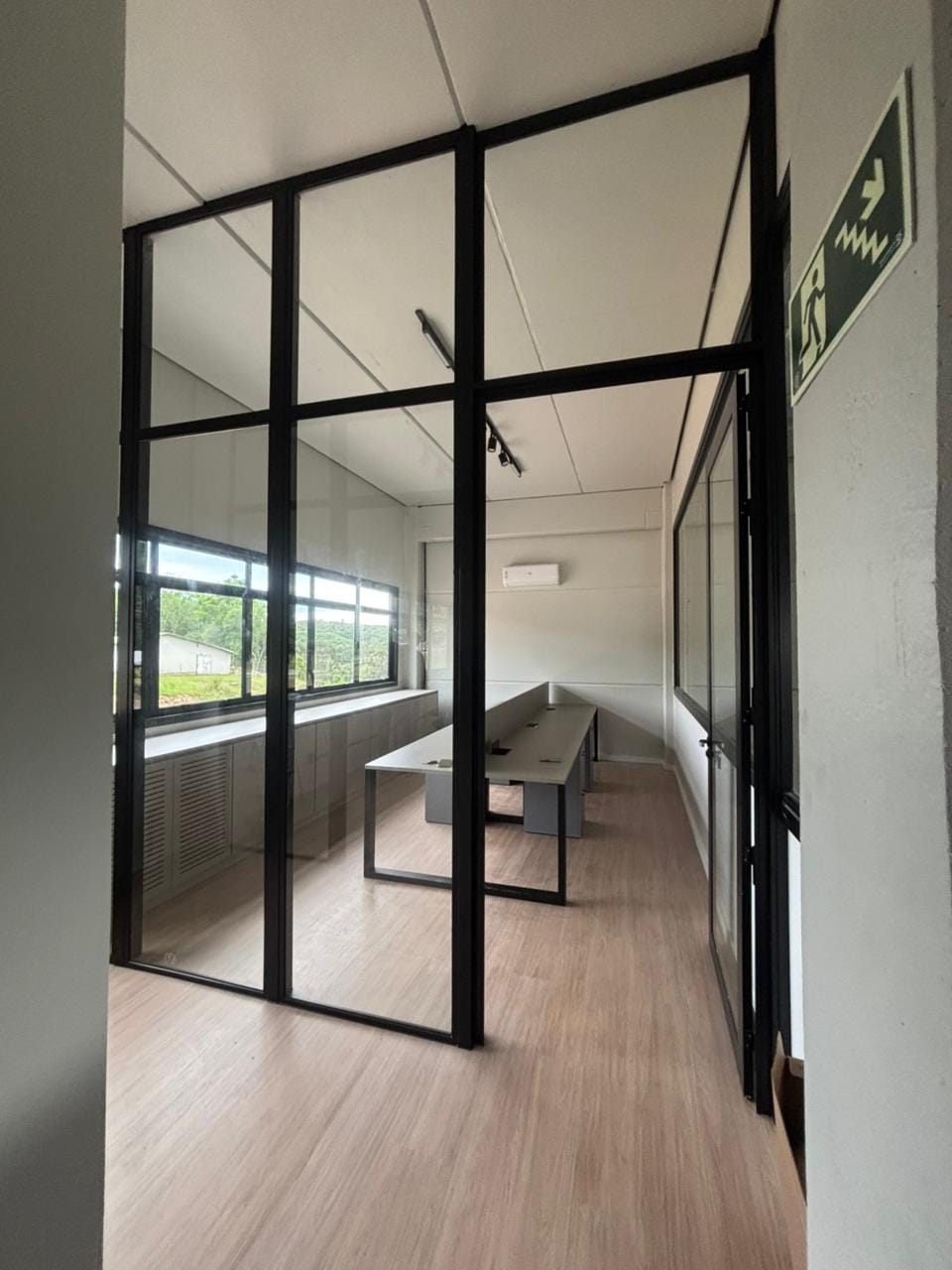 Sala com divisórias em vidro e perfil preto e mesa de reunião