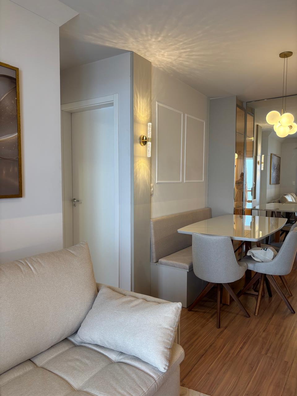Sala de estar com sofá claro e mesa de jantar ao fundo