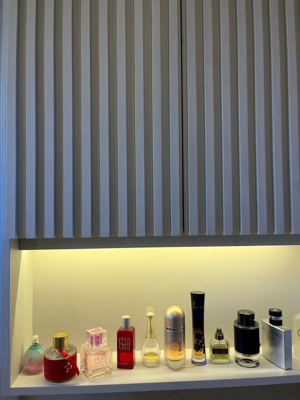 Nicho iluminado com perfumes sob o ripado